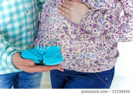 Pregnant couple holding shoes in hands Pregnant couple holding shoes in hands 37230430