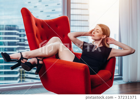 Elegant young woman relaxing on red stylish 37231371