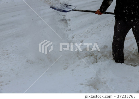 Man cleaning snow from a walkway with  37233763