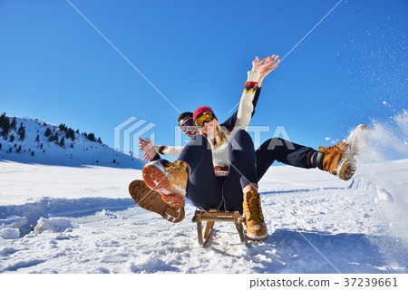 Young Couple Sledding And Enjoying On Sunny Winter 37239661