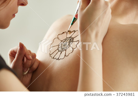 Mehndi master drawing with henna on model's back 37243981