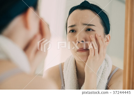 Young woman looking at mirror rough skin Acne skin trouble Young woman looking at mirror rough skin Acne skin trouble 37244445