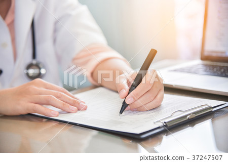 doctor is using laptop and writing something doctor is using laptop and writing something 37247507