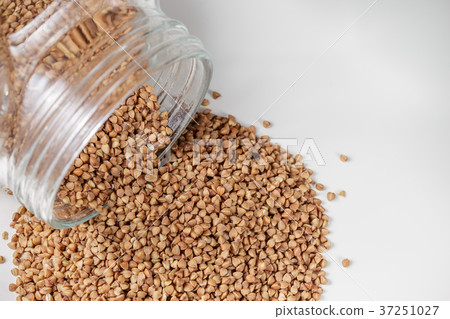 Uncooked buckwheat scattered from jar on table Uncooked buckwheat scattered from jar on table 37251027