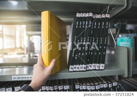 woman's hand taking book from shelf 37251824