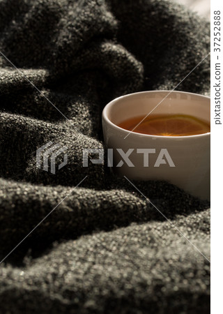 Close up white cup of tea wrapped in blanket 37252888
