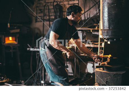 male blacksmith shaping metal in hammer machine male blacksmith shaping metal in hammer machine 37253842