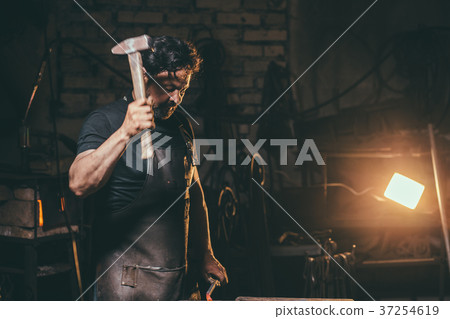 Blacksmith forging molten metal on the anvil in Blacksmith forging molten metal on the anvil in 37254619