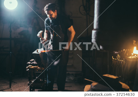 Senior blacksmith forging molten metal on the 37254630