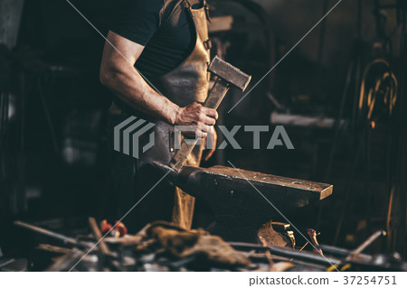 Blacksmith working on metal on anvil at forge Blacksmith working on metal on anvil at forge 37254751