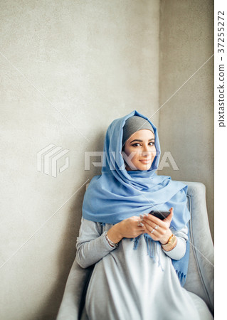 Young woman sitting and holding mobile phone 37255272