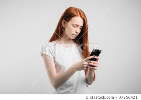 Portrait of a smiling redhead woman holding 37256421