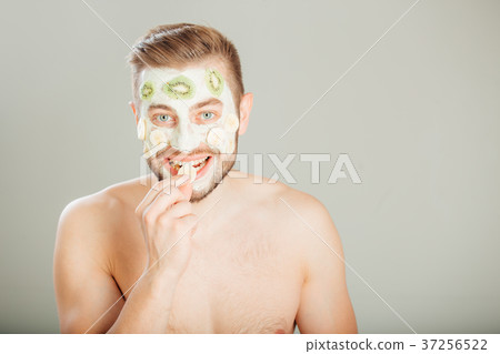 Man with cosmetic mask on face, gray background Man with cosmetic mask on face, gray background 37256522
