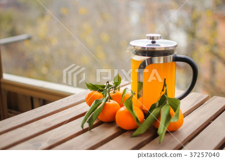 Glass teapot with orange drink and tangerines Glass teapot with orange drink and tangerines 37257040