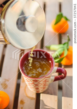 Pouring tangerine tea into cup on wooden table Pouring tangerine tea into cup on wooden table 37257041