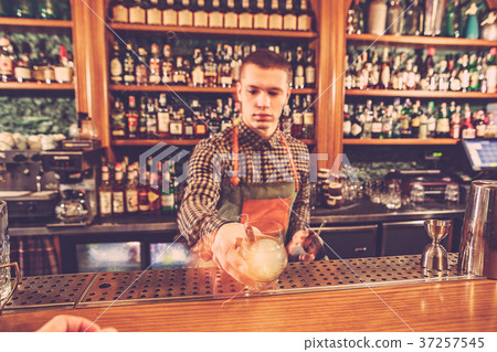 Barman making an alcoholic cocktail at the bar Barman making an alcoholic cocktail at the bar 37257545