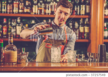 Expert barman is making cocktail at night club. 37257549
