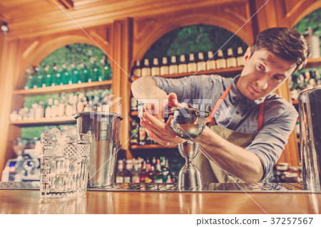 Expert barman is making cocktail at night club. 37257567