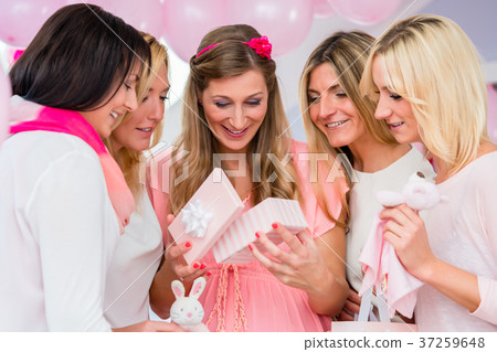 Pregnant woman opening present box on baby shower Pregnant woman opening present box on baby shower 37259648
