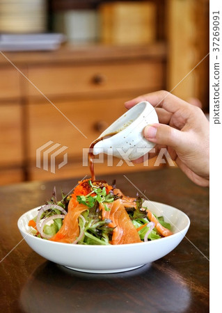 Pouring Japanese dressing over salmon salad 37269091
