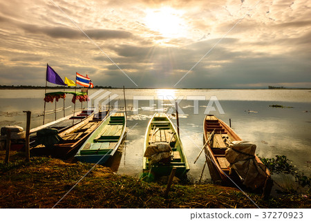 wooden rowboat in the calm water of lake at sunset 37270923