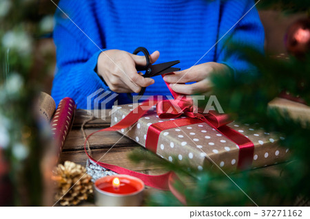 Cutting red ribbon for wrapping present Cutting red ribbon for wrapping present 37271162
