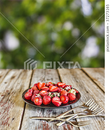 A plate of ripe strawberries a table with a place 37273165