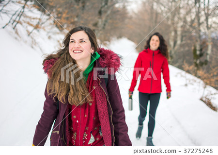 Two girls on a hiking trip on snowy mountain 37275248