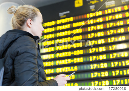 Woman at airport in front of flight information 37280018