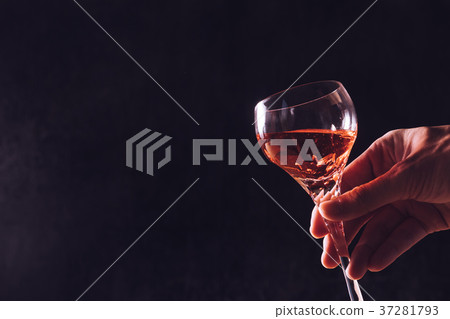 Male hand holding a glass of wine on black Male hand holding a glass of wine on black 37281793