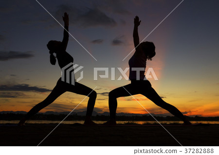 Silhouette Two women's yoga together during sunrise 37282888