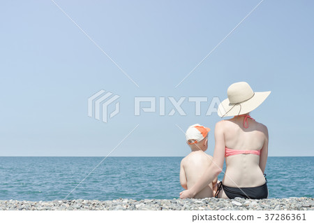 Mom and son sitting on the beach and admire sun 37286361