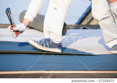 Roof construction craftsman sticking waterproof sheet with hammer tucker 37288975