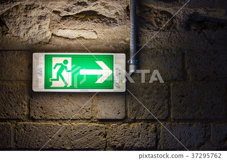 emergency exit light green sign on brick wall in 37295762