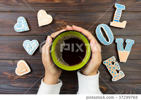Female hands with coffee and heart shaped cookies Female hands with coffee and heart shaped cookies 37299768