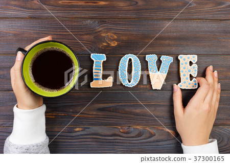 Female hands with coffee and heart shaped cookies Female hands with coffee and heart shaped cookies 37300165