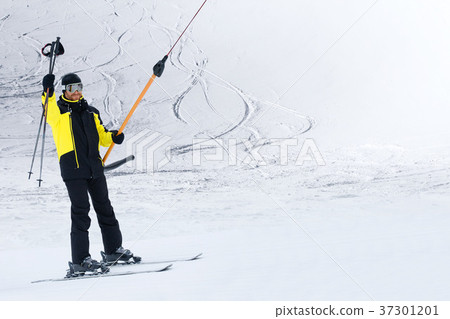 Happy skier using T-bar ski drag lift 37301201
