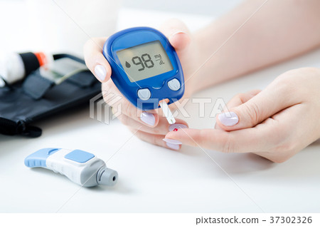 Woman checking blood sugar level by glucometer 37302326