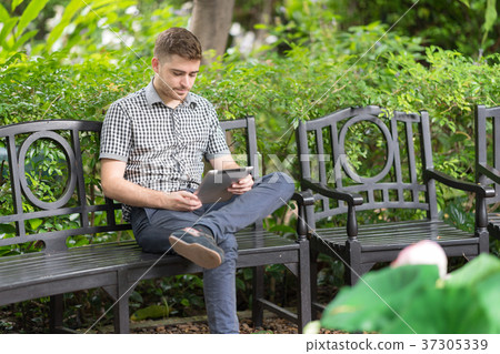 Man using digital tablet in the garden park. Man using digital tablet in the garden park. 37305339