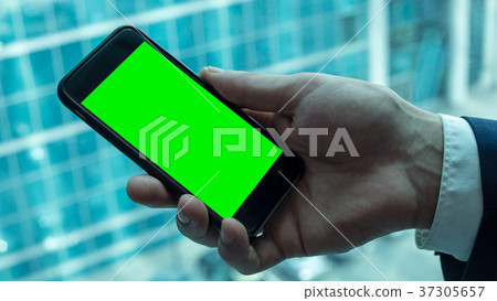 Man holding black smartphone with green screen Man holding black smartphone with green screen 37305657