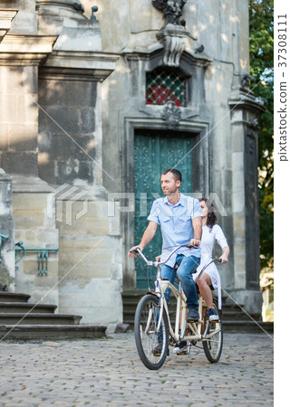 Young couple on retro tandem bicycle at the street city 37308111