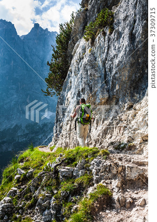 Young man backpacker walking on mountain trail Young man backpacker walking on mountain trail 37309715