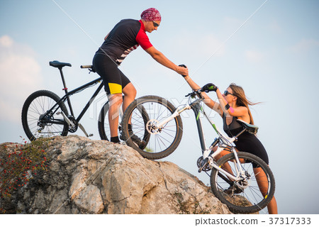 Bicyclist helping to his partner with a mountain bike 37317333