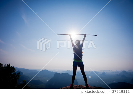 hiker stand on sunrise mountain peak rock edge 37319311