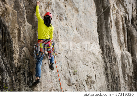 female rock climber climbing on mountain cliff 37319320