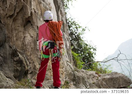 rock climber standing with climbing gears and rope 37319635