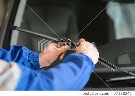 Technician is changing windscreen wipers on a car Technician is changing windscreen wipers on a car 37328245