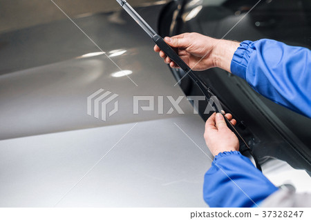 Technician is changing windscreen wipers on a car 37328247