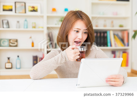 一個女人在一個房間裡看一個平板電腦驚訝她 一個女人在一個房間裡看一個平板電腦驚訝她 37329966