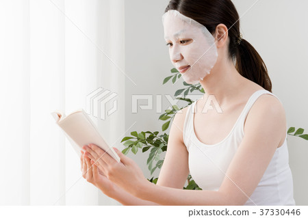 Woman doing face mask, reading 37330446